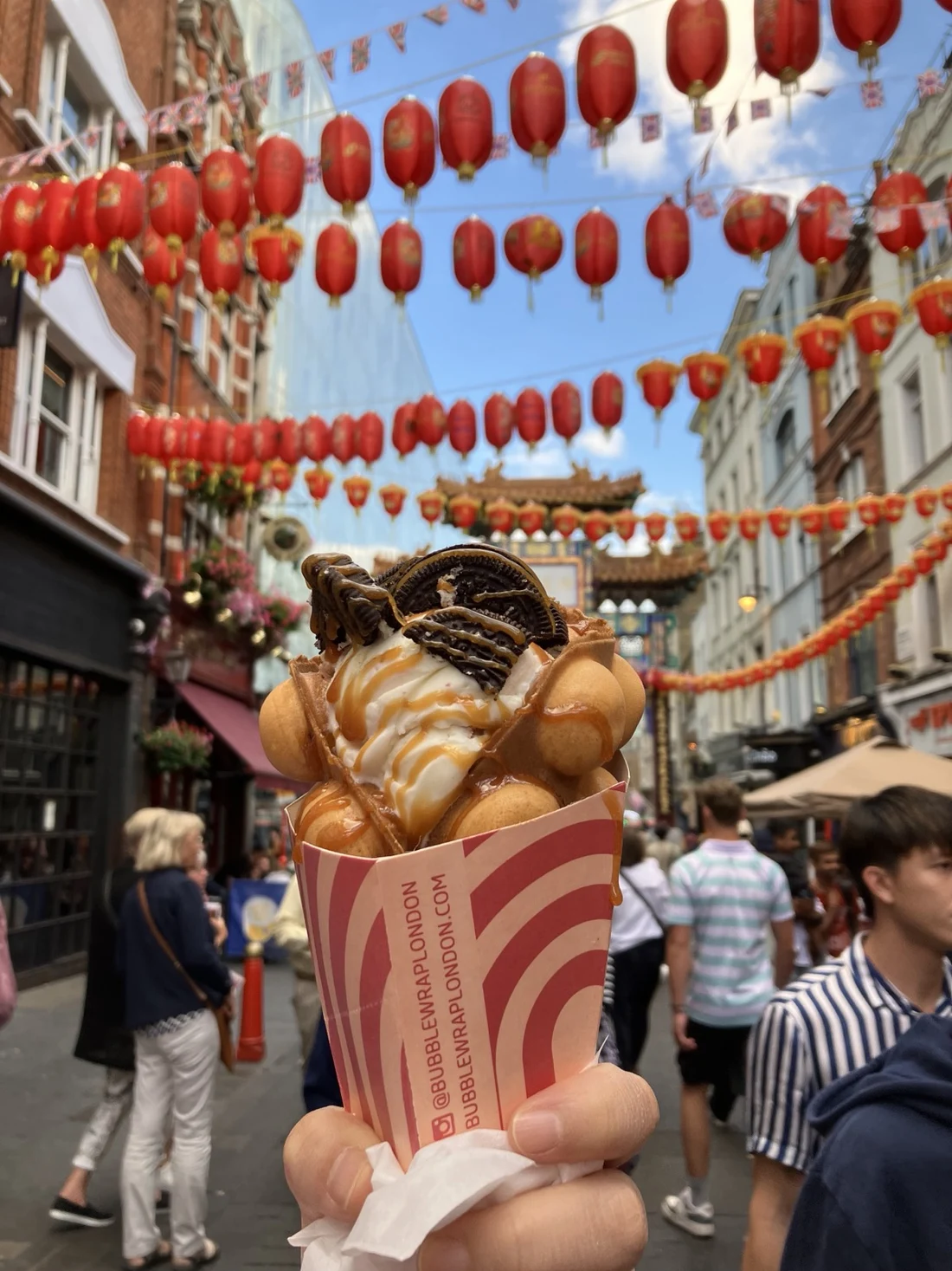 A bubble waffle held beneath rows of red lanterns