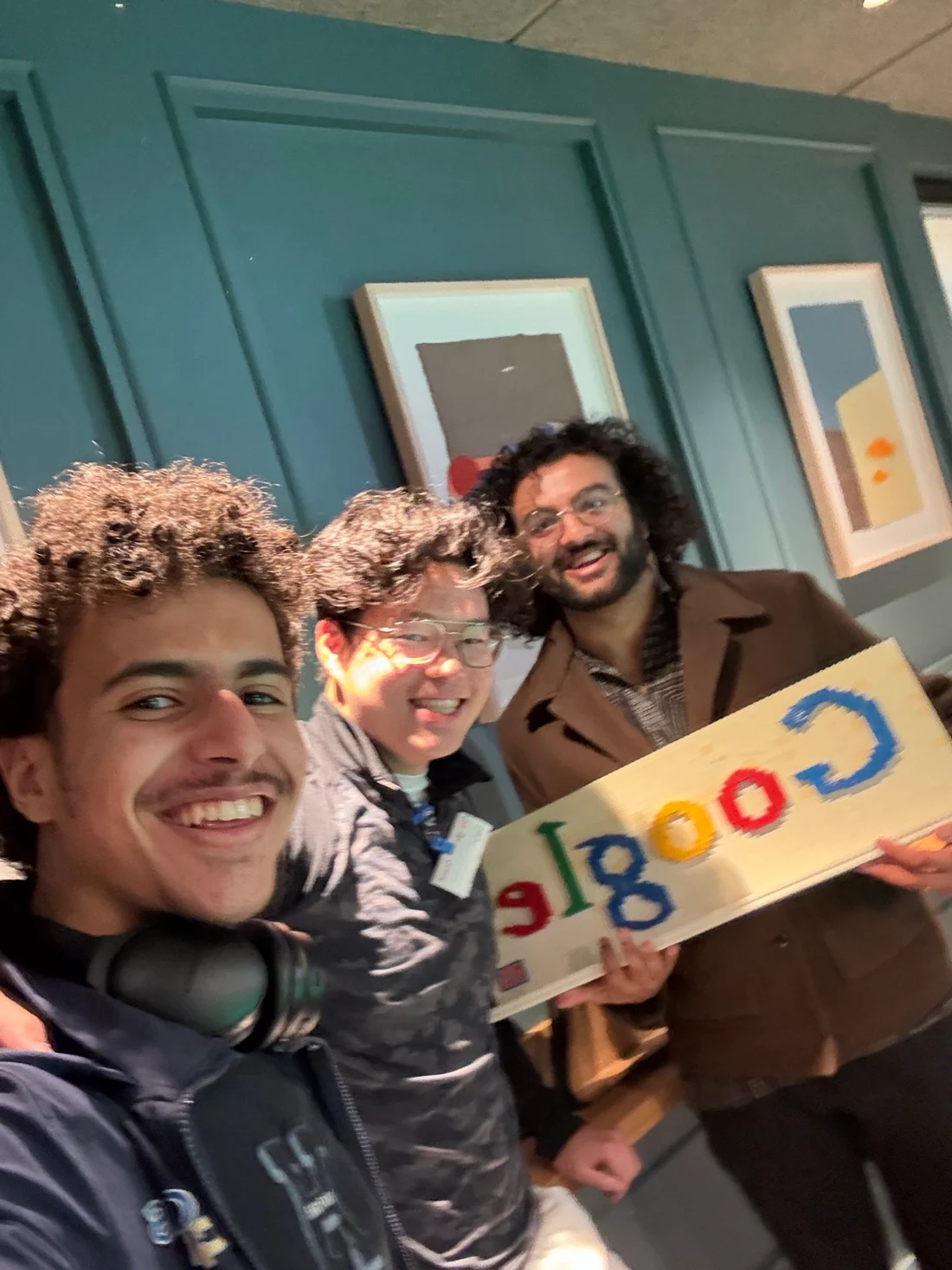 Three friends smiling together with a Google sign