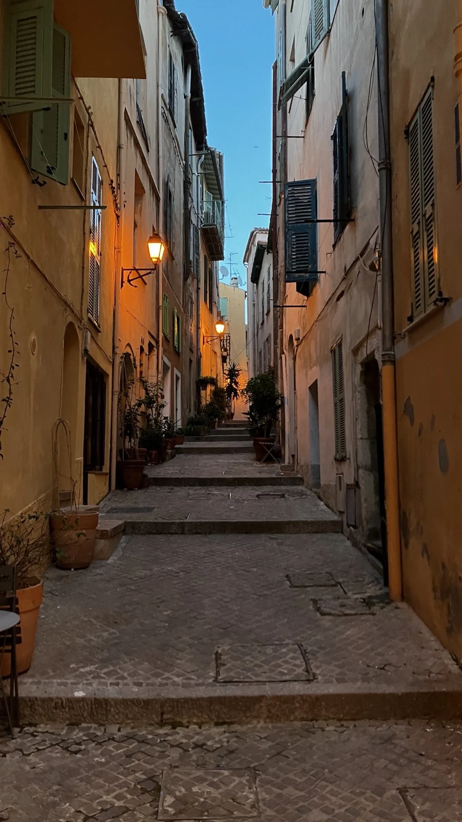 A narrow stone stairway between colorful buildings at dusk